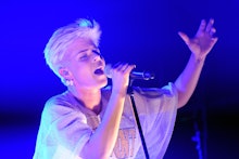 Robyn holding a microphone while singing at her concert