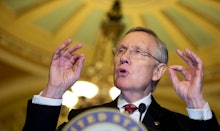 Harry Reid with his hands raised giving a speech behind a podium