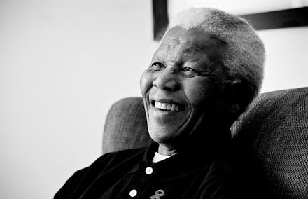 Black and white closeup photo of Nelson Mandela (Madiba) sitting in a chair and smiling 