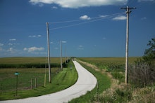 An isolated road with green grass fields around it in the U.S.
