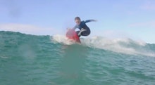 A sick 6-year-old surfing in the ocean on a bright sunny day