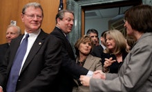James Inhofe walking into a room as a man and woman behind him are shaking hands 