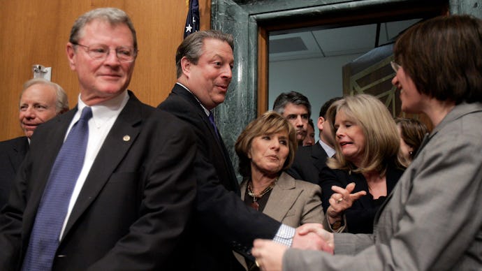 James Inhofe walking into a room as a man and woman behind him are shaking hands 