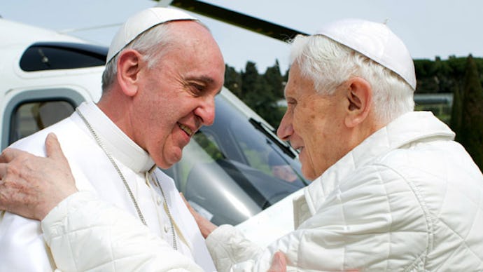 Pope Francis and Pope Benedict XVI greeting each other in front of a helicopter