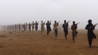 Al-Qaeda in Iraq marching through the desert with rifles in their arms