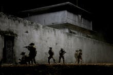 A screenshot with solider walking around a building from the movie 'Iraq in Fragments'