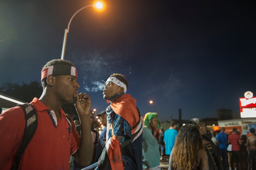 A lot of people smoking marijuana on a street