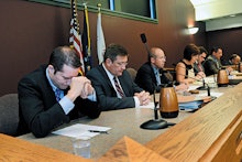 Chairmen and chairwomen doing a prayer before a local government meeting