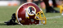 Washington Redskins helmet, with a Native American character on it, laying on the football field.