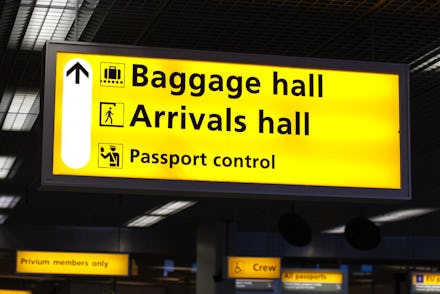 Yellow sign in an airport that shows the way to the baggage hall, arrivals hall and passport control