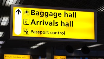 Yellow sign in an airport that shows the way to the baggage hall, arrivals hall and passport control