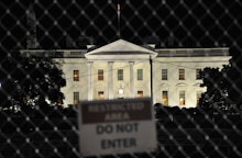 A 'do not enter sign' on the fence with the White House behind it.