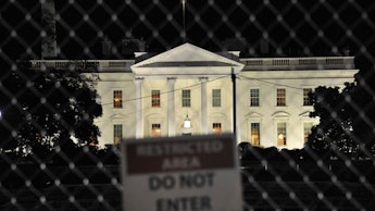 A 'do not enter sign' on the fence with the White House behind it.