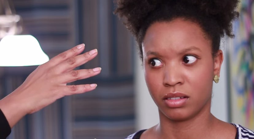 A black woman baffled as a hand reaches toward her Afro-textured hair 