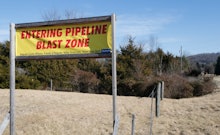 "Entering pipeline blast zone" sign on a grass field