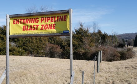 "Entering pipeline blast zone" sign on a grass field