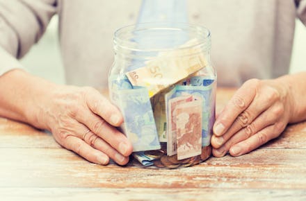 An older man sitting and holding a box full of money