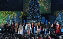 Country artists on a stage with a Christmas tree behind them performing country Christmas songs