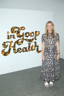 Gwyneth Paltrow standing in her company in front of a sign that says "Goop in Health"