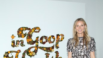 Gwyneth Paltrow standing in her company in front of a sign that says "Goop in Health"