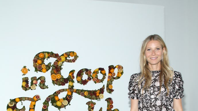 Gwyneth Paltrow standing in her company in front of a sign that says "Goop in Health"