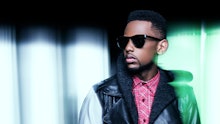 Fabolous wearing dark shades, red checked shirt and a black-and-white leather jacket