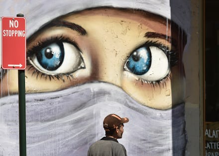A mural of a woman wearing a hijab with only her eyes seen, for awareness on "honor killings"