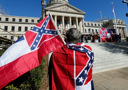 A man with two old Mississippi flags in front of the state Capitol in Jackson, Mississippi