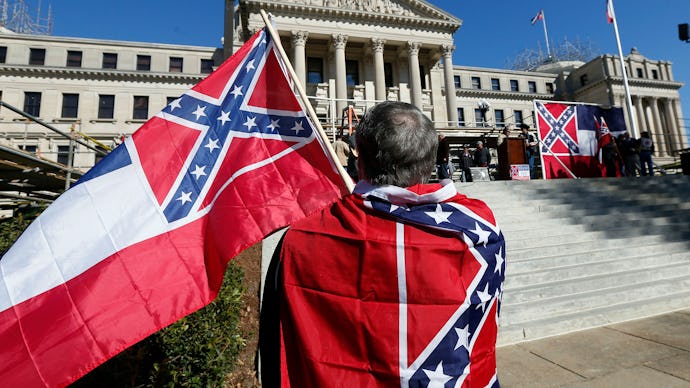 A man with two old Mississippi flags in front of the state Capitol in Jackson, Mississippi