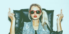 A blonde girl with a ponytail, red lipstick, and sunglasses showing her middle fingers for the lates...