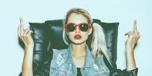 A blonde girl with a ponytail, red lipstick, and sunglasses showing her middle fingers for the lates...