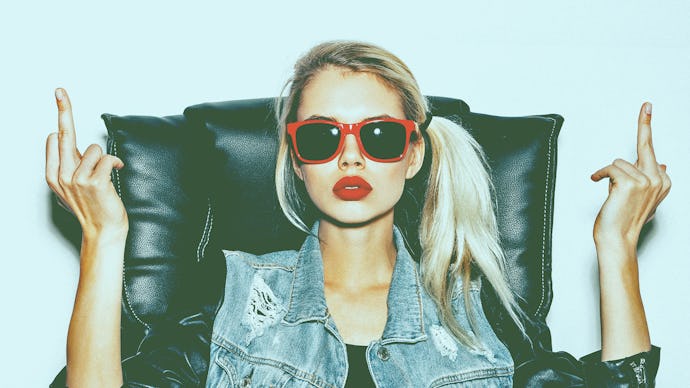 A blonde girl with a ponytail, red lipstick, and sunglasses showing her middle fingers for the lates...