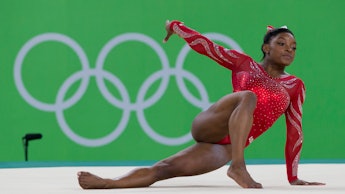 Simone Biles, Rio's Olympics gymnastics favorite, leaning on her hand while posing in a red suit