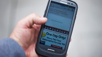 A man holding a smart phone that he bought as part of a cyber monday scam