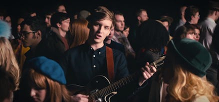 George Ezra playing his guitar while standing in the crowd