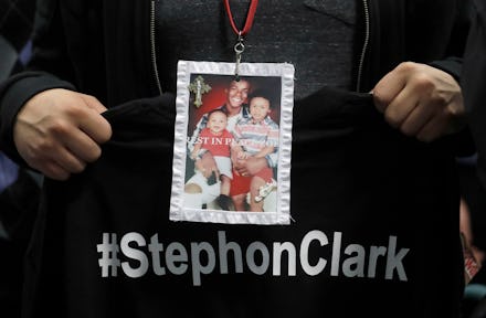 A man holding a black t-shirt with white "#StephonClark" text