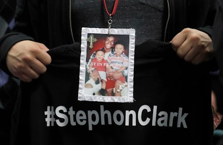 A man holding a black t-shirt with white "#StephonClark" text