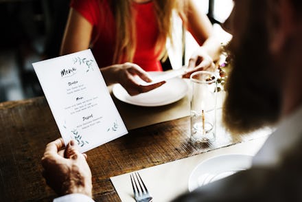 A man and a woman in a restaurant checking out the menus