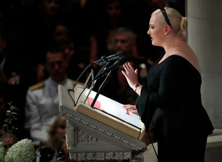 Meghan McCain in a black dress standing on a pedestal and giving a speech