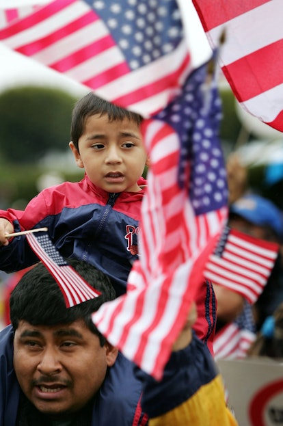 Latino father and son holding American flags