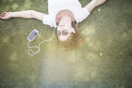 A girl lying on grass and listening to music on earphones