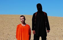 Islamic State's soldier dressed fully in black standing next to a hostage