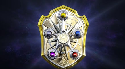 A golden 'Fire Emblem' with a yellow, blue, red, purple and grey crystal