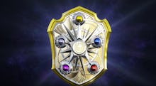 A golden 'Fire Emblem' with a yellow, blue, red, purple and grey crystal