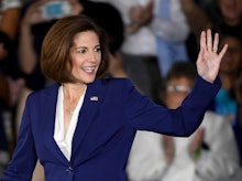 Cortez Masto in a white shirt and blue blazer waving at an audience