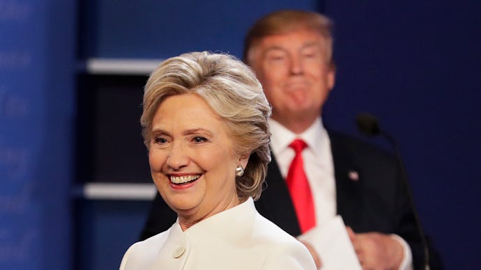 Hillary Clinton in a white blazer and Donald trump blurred in the background