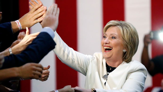 Hillary Clinton laughing and shaking hands at a political rally