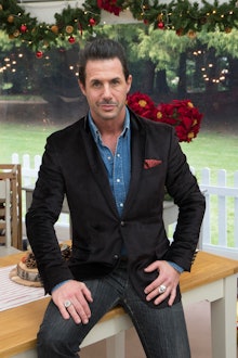 Johnny Iuzzini sitting on a table in a black blazer and a blue button up shirt