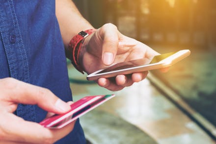 A person holding their phone and credit card, applying for a credit card for the first time