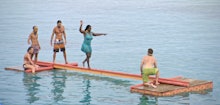A scene from 'Survivor: Game Changers' with people on a wooden deck on water